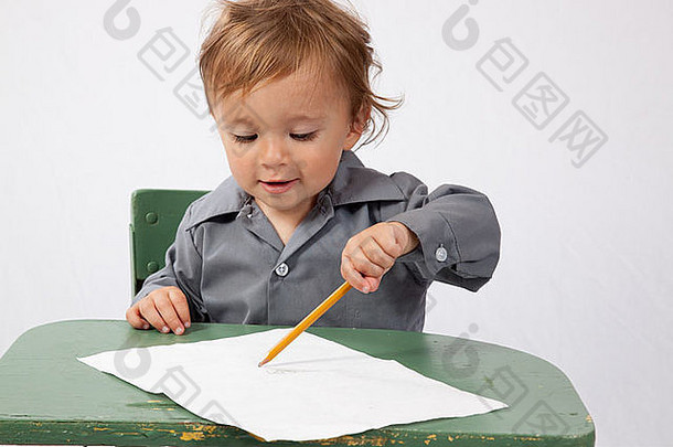 年轻的男孩坐着桌子上一块纸铅笔快乐