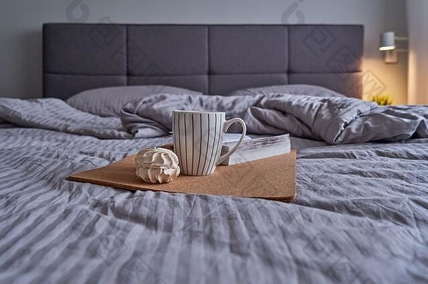 舒适的卧室大床上软床头板米色颜色咖啡杯子书早....晚上例程概念
