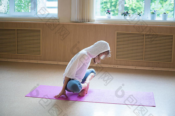 年轻的苗条的女人白色罩坐着瑜伽席莲花位置倾斜脚趾