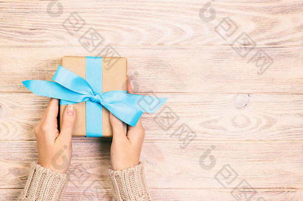 女人手给包装情人节假期手工制作的现在纸蓝色的丝带现在盒子装饰礼物白色木表格