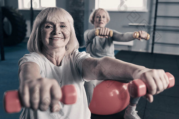 上了年纪的女人锻炼哑铃健身房