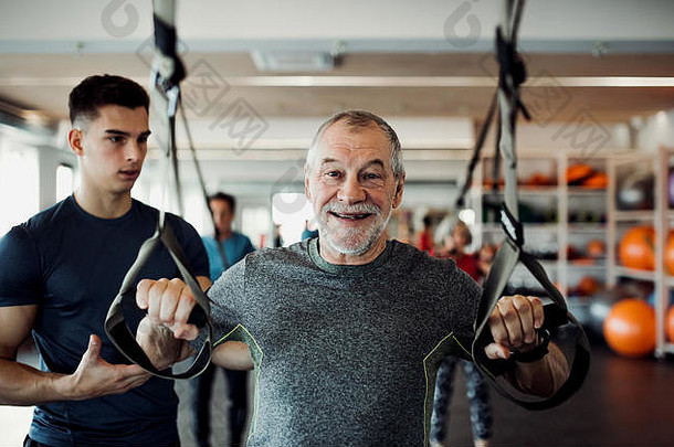 集团快乐的老年人健身房年轻的教练锻炼trx