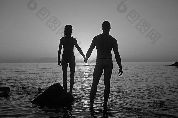假期夫妇走日落海滩爱持有手快乐年轻的夫妇女人高加索人男人。