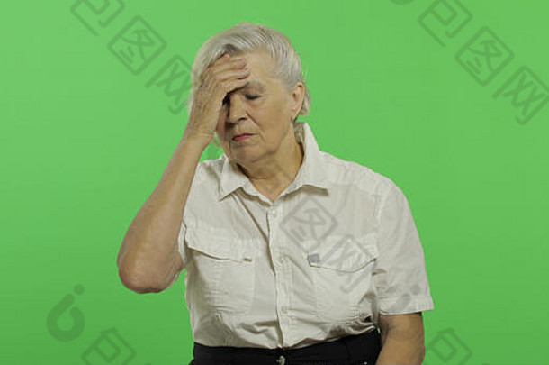 上了年纪的女人遭受头疼疼痛麻烦漂亮的祖母白色衬衫的地方标志文本浓度关键绿色屏幕背景概念情绪