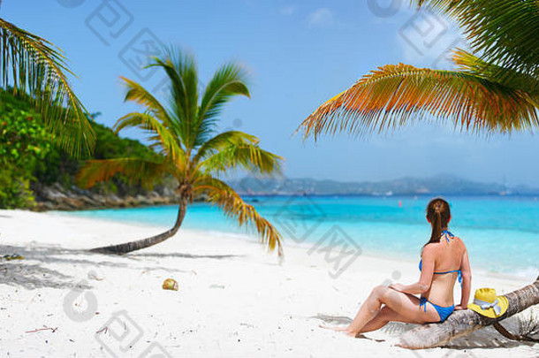 回来视图年轻的美丽的女人坐着棕榈树放松白色沙子热带海滩