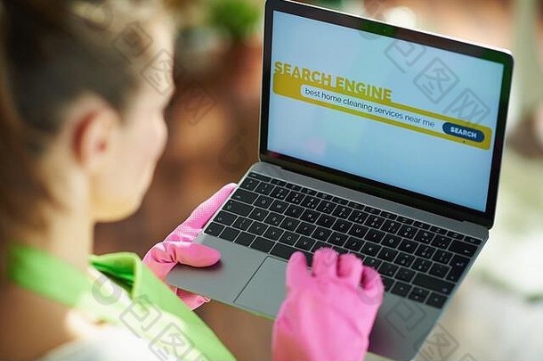 特写镜头女人绿色围裙粉红色的橡胶手套房子阳光明媚的一天搜索清洁服务移动PC