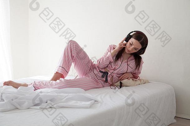 浅黑肤色的女人女人粉红色的睡衣听音乐耳机