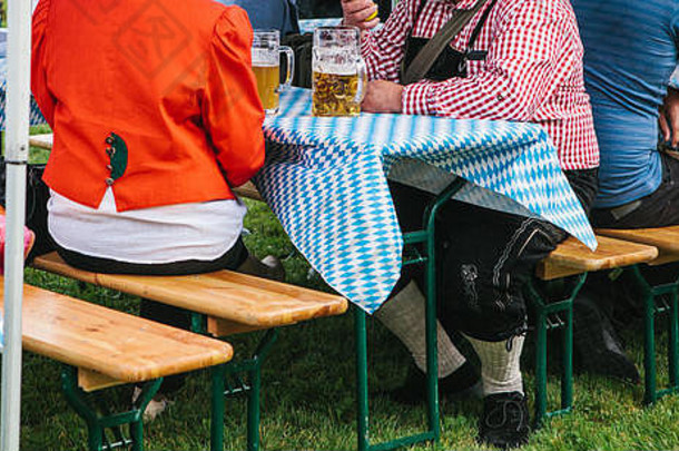 人传统的西装喝啤酒在户外德国啤酒节庆祝活动