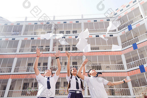 快乐成功的少年学校学生扔论文庆祝活动教育学校院子里