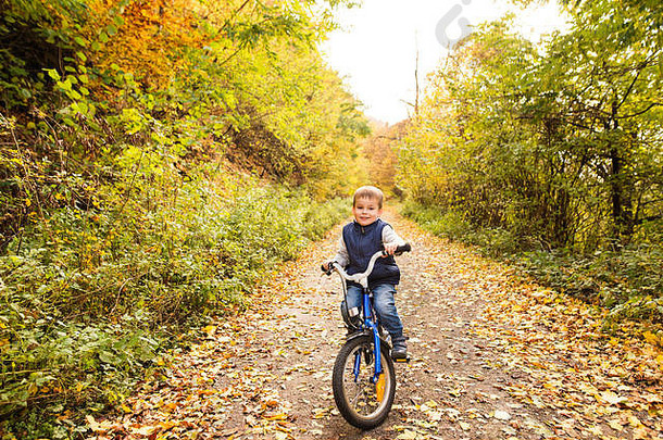可爱的男孩骑自行车<strong>阳光</strong>明媚的秋天公园