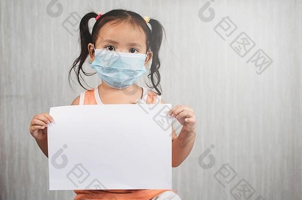 亚洲女孩穿外科手术面具持有空白白色纸概念孩子健康护理病毒疾病爆发