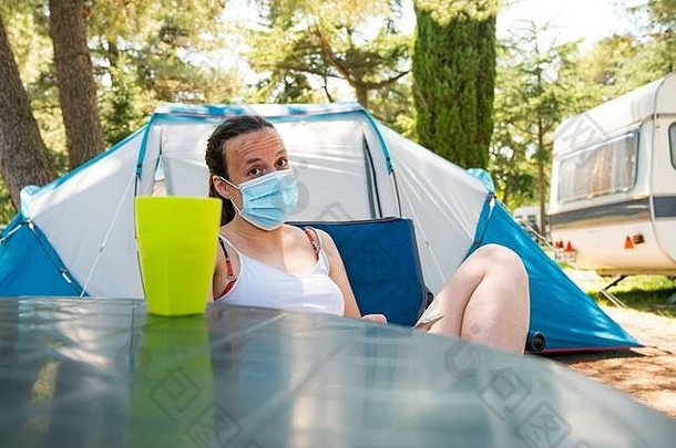 女人穿医疗面具坐着前面野营帐篷度假胜地