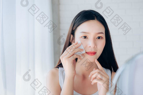 年轻的美亚洲女人清洁脸棉花镜子清晰的脸护肤品微笑早....白色卧室