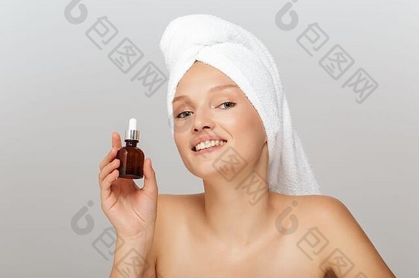 肖像年轻的微笑女人化妆白色毛巾头持有液体瓶手幸福的相机灰色的背景