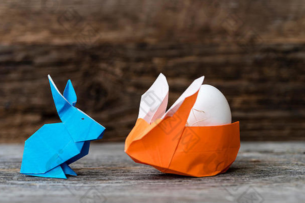 色彩斑斓的折纸复活节兔子兔子使纸橙色蓝色的大小父婴儿蛋抱着女孩橙色