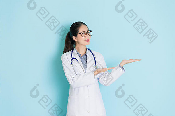 微笑漂亮的女人医生使展示手势显示空区域孤立的蓝色的背景