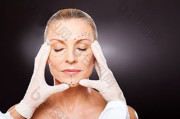 塑料外科医生检查中间岁的女人脸化妆品手术