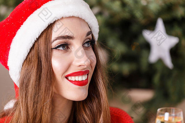 有吸引力的圣诞节女人穿圣诞老人他红色的毛衣坐着香槟地板上舒适的一年云杉一年圣诞节假期记忆礼物购物折扣商店雪少女圣诞老人老人化妆发型狂欢节