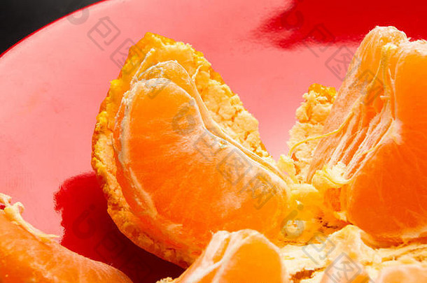 橘子去皮橘子橘子片红色的板黑色的背景