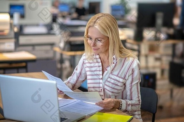 金发女郎女人坐着移动PC阅读论文