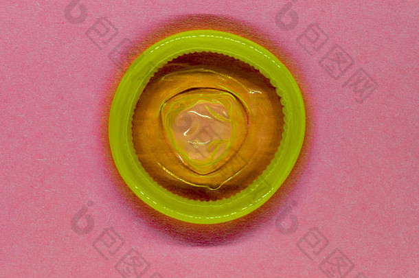 黄色的颜色避孕套粉红色的背景表面