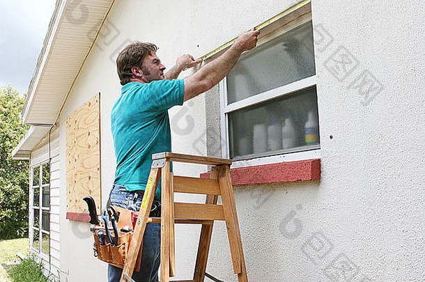 男人。测量窗户飓风百叶窗胶合板