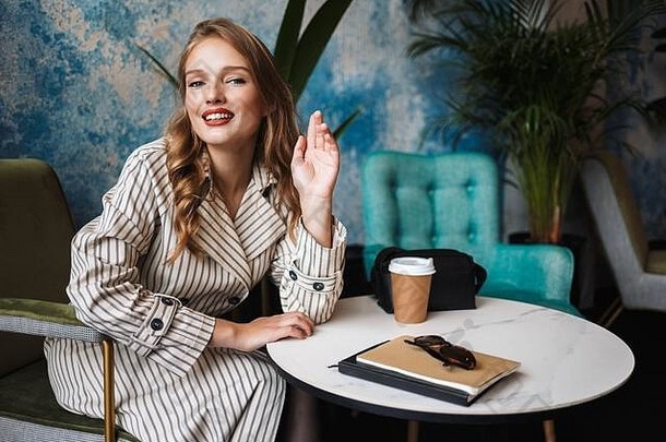 年轻的漂亮的女人波浪头发条纹沟外套幸福的相机持有手支出时间现代咖啡馆