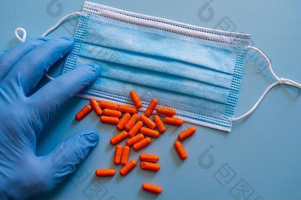 手手套显示小集团橙色药用药片保护外科手术面具光蓝色的背景