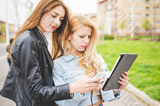 一半长度年轻的金发女郎浅黑肤色的女人女孩走城市<strong>平板电脑</strong>采取自拍屏幕技术沟通社会网络概念