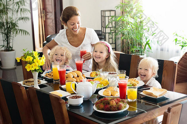 健康的家庭早餐首页妈妈。孩子们吃热带水果烤面包面包奶酪香肠孩子们喝新鲜的按下汁阳光明媚的