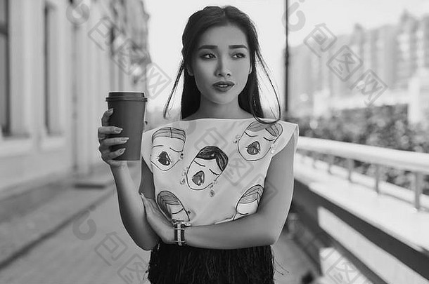 肖像可爱的华丽的亚洲女人时尚衣服走明亮的欧洲街杯咖啡