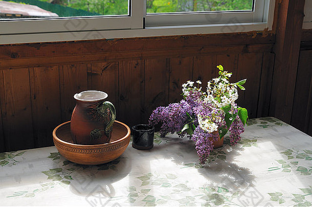 花束新鲜的淡紫色盛开的樱桃站粘土壶表格窗口木墙餐具