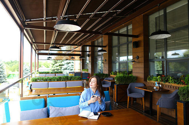高加索人学生坐着咖啡馆笔记本智能手机喝咖啡