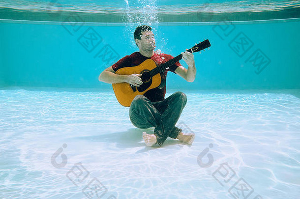 年轻的男人。玩音乐吉他唱歌首歌水下