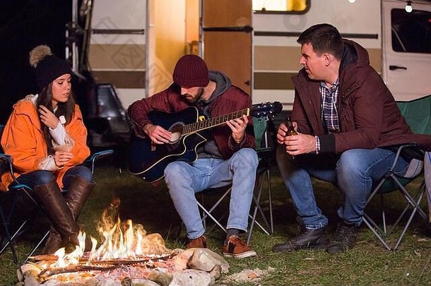 朋友放松玩吉他营火复古的露营者的背景光灯泡