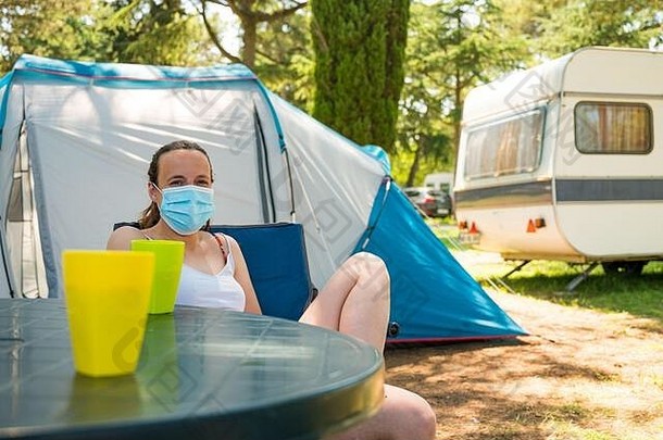 女人穿医疗面具坐着前面野营帐篷度假胜地