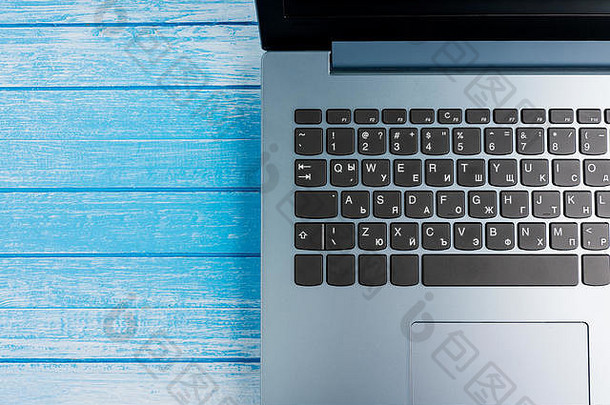 梯度蓝色的品牌移动PC黑色的键盘特写镜头蓝色的木表面工作室拍摄