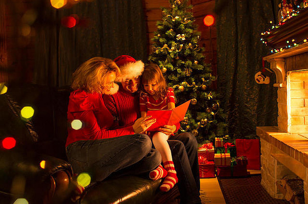 家庭读故事圣诞节时间坐着沙发前面壁炉
