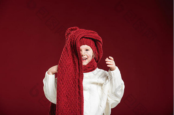 美丽的金发碧眼的女孩玩冬天温暖的他围巾红色的背景