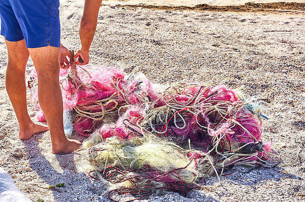 纠结的混乱钓鱼网塑料绳子碎片洗沿海海滩保存地球股票图片