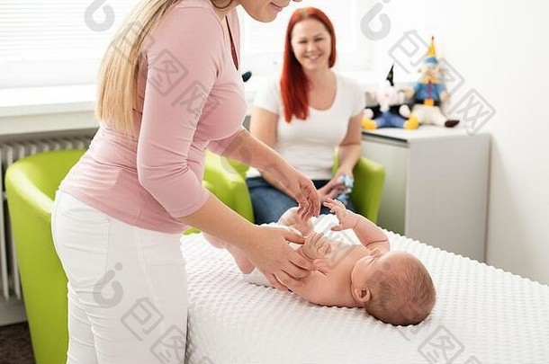 女按摩治疗师医生检查新生儿婴儿男孩妈妈。看背景婴儿按摩概念