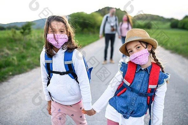 家庭小女儿旅行在户外自然穿脸面具
