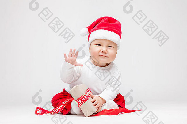 可爱的年轻的婴儿男孩穿圣诞老人他开放圣诞节礼物