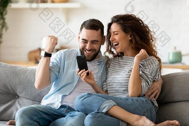 兴奋夫妇持有智能手机庆祝在线彩票赢得