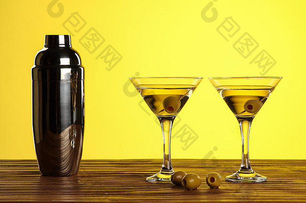 鸡尾酒马提尼眼镜绿色橄榄瓶木表面黄色的背景复制空间