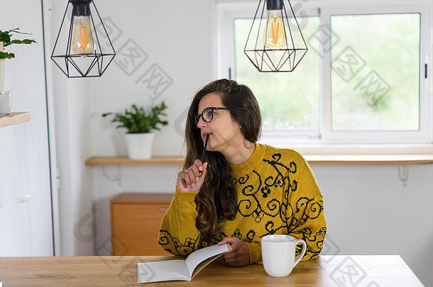 女人眼镜深思熟虑的的姿势持有铅笔空白笔记本白色杯子前木工作台内部房子