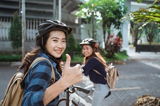 亚洲年轻的女人拇指穿头盔袋准备好了校园折叠自行车