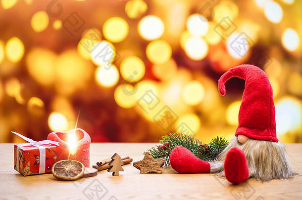 红色的坐着圣诞节精灵散景灯背景包围圣诞节装饰礼物盒子点燃出现蜡烛