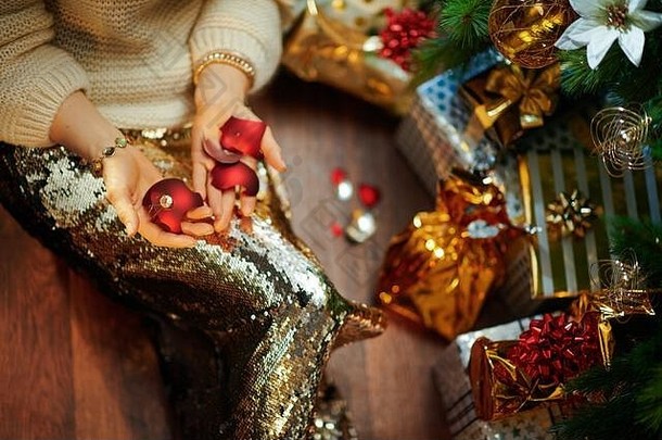 特写镜头时尚的中间年龄家庭主妇黄金金片裙子白色毛衣装饰圣诞节树现在盒子持有破碎的基督