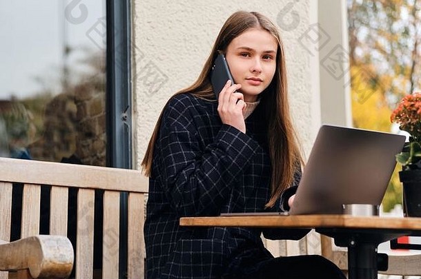 美丽的女孩会说话的手机工作移动PC户外咖啡馆